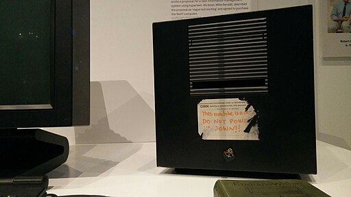 Photo of a desktop computer with a handwritten sticker, partly scraped off.