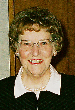 Photo of a woman with curly hair, glasses, and a pearl necklace